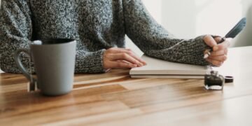 Person writing notes at a table, illustrating mindful digital habits